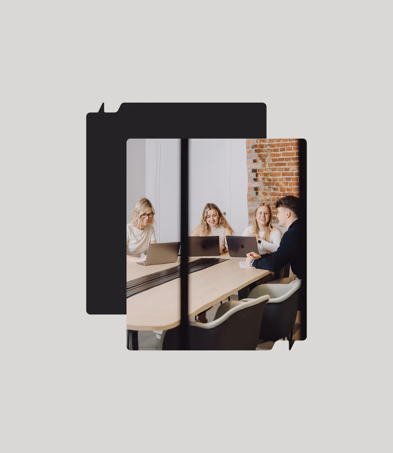 Vier collega’s van Miles & Mates lachen en overleggen rond een houten tafel met laptops, tegen een muur van witte en bakstenen accenten.