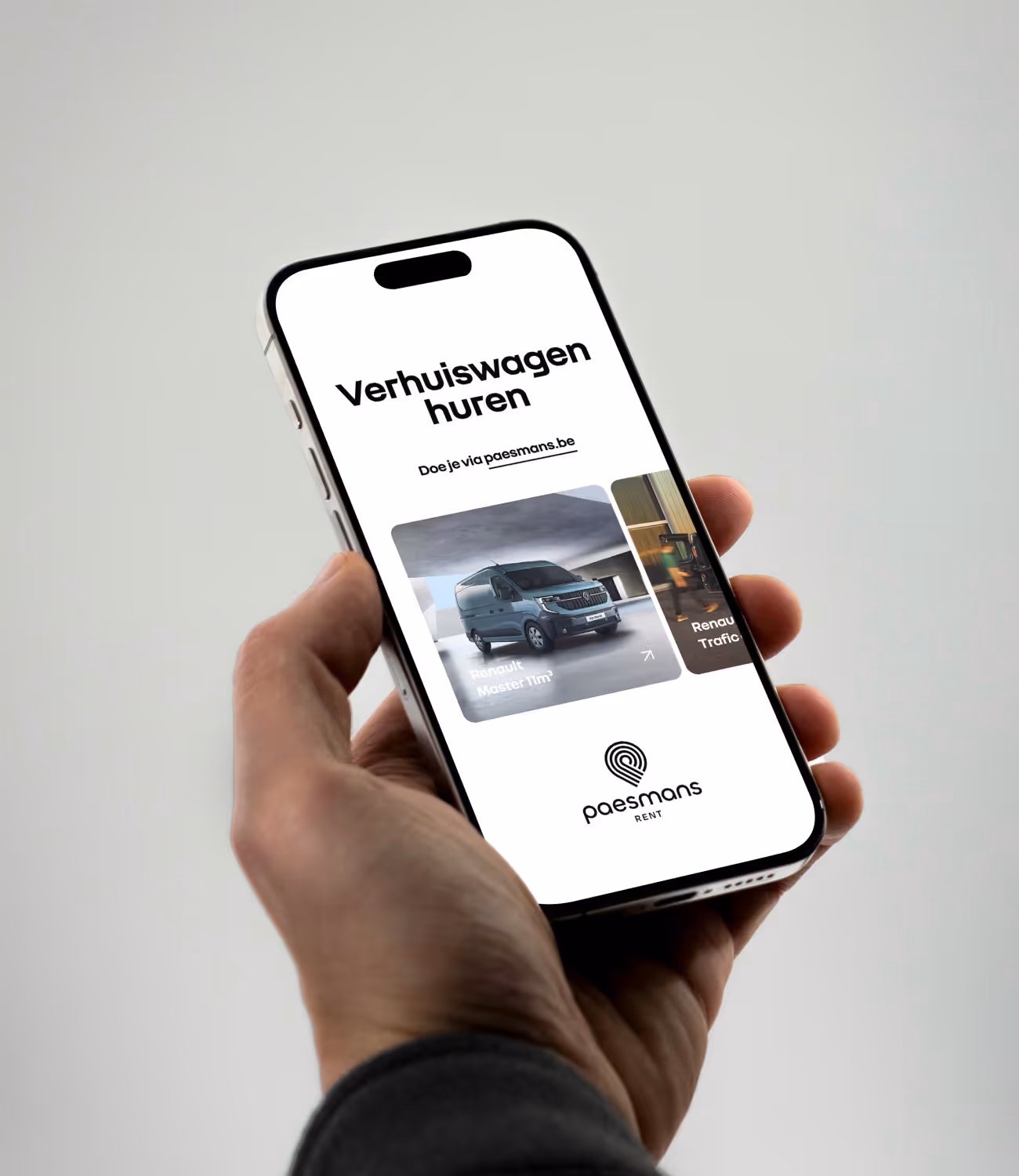 Close-up van een hand met smartphone waarop de Paesmans Rent-website te zien is, met het aanbod verhuiswagens.