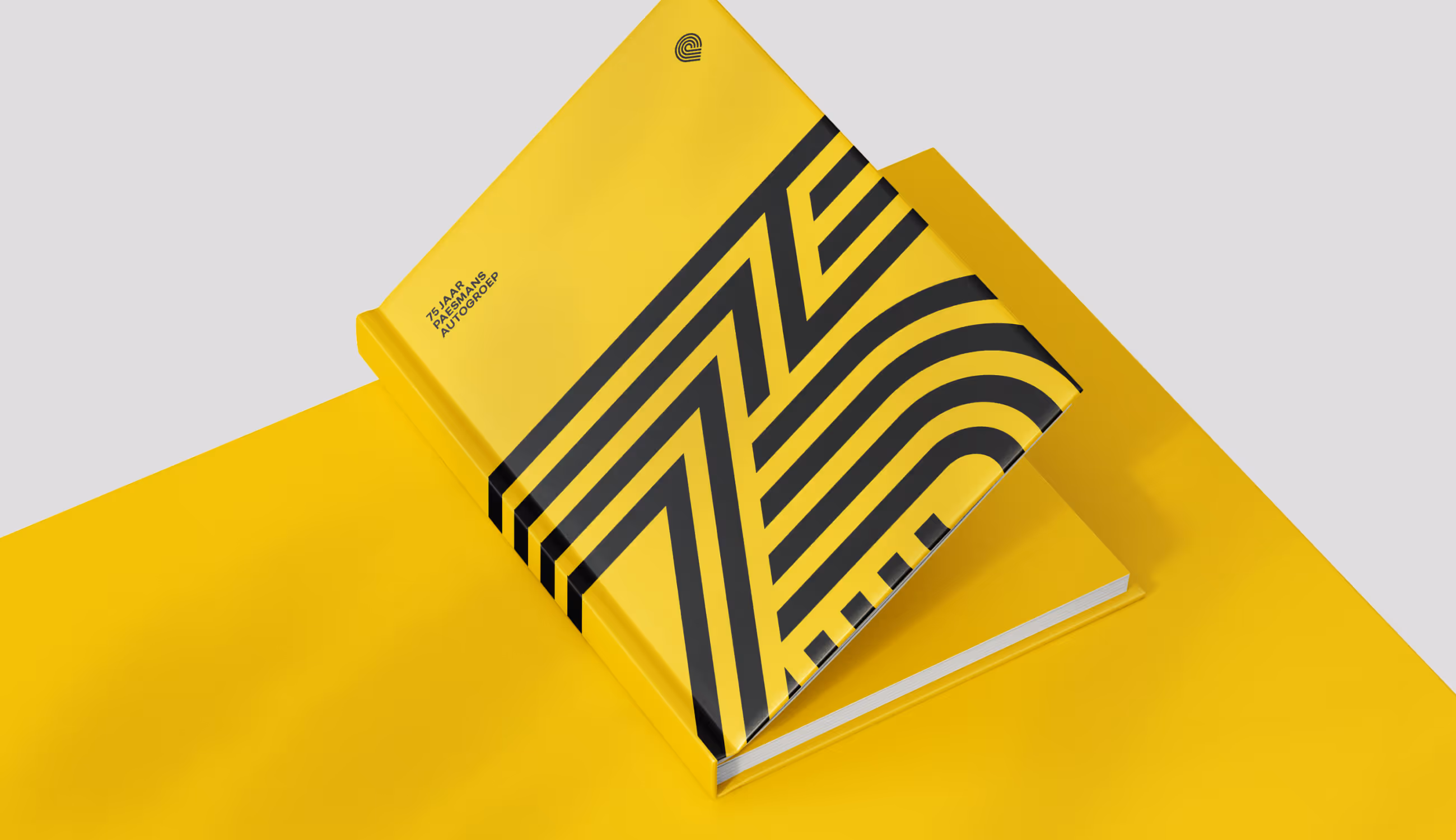 Geel koffietafelboek met het zwarte jubileumpatroon en de tekst “75 jaar Paesmans Autogroep” op een gele ondergrond.