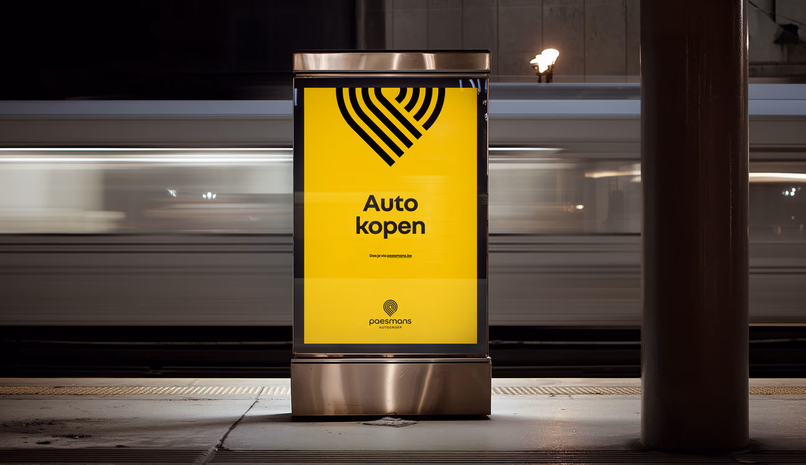 Gele verlichte poster met het zwarte Paesmans-patroon en de tekst “Auto kopen”, in een stedelijke omgeving met voorbijrijdende trein.