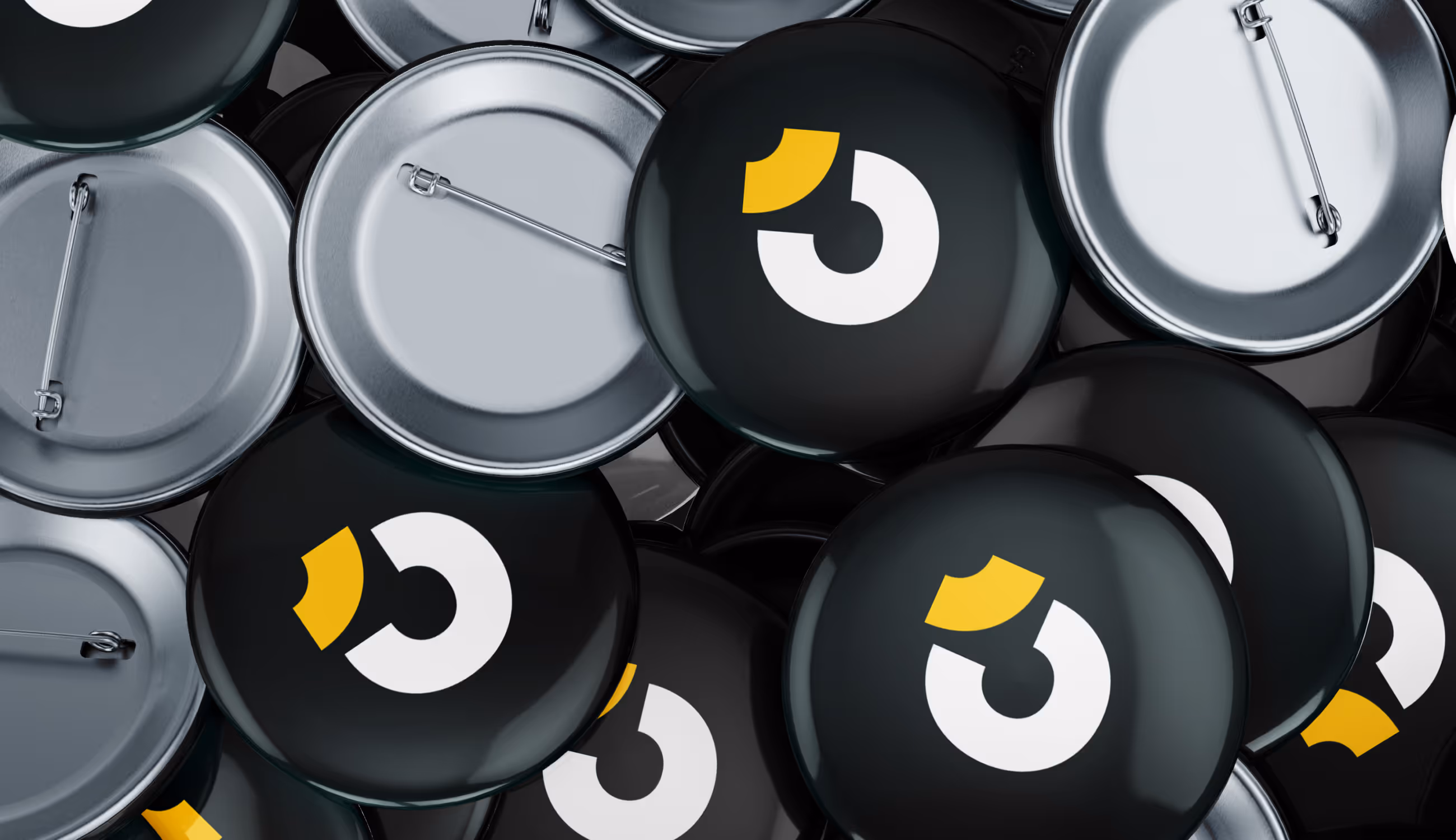 Close-up van stapel metalen buttons met Tricore-logo in wit en geel op zwarte achtergrond.