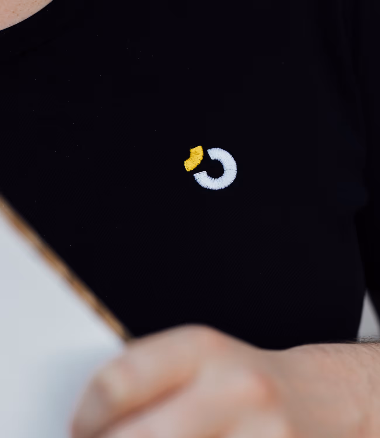 Close-up van Tricore-logo geborduurd op zwarte shirt.