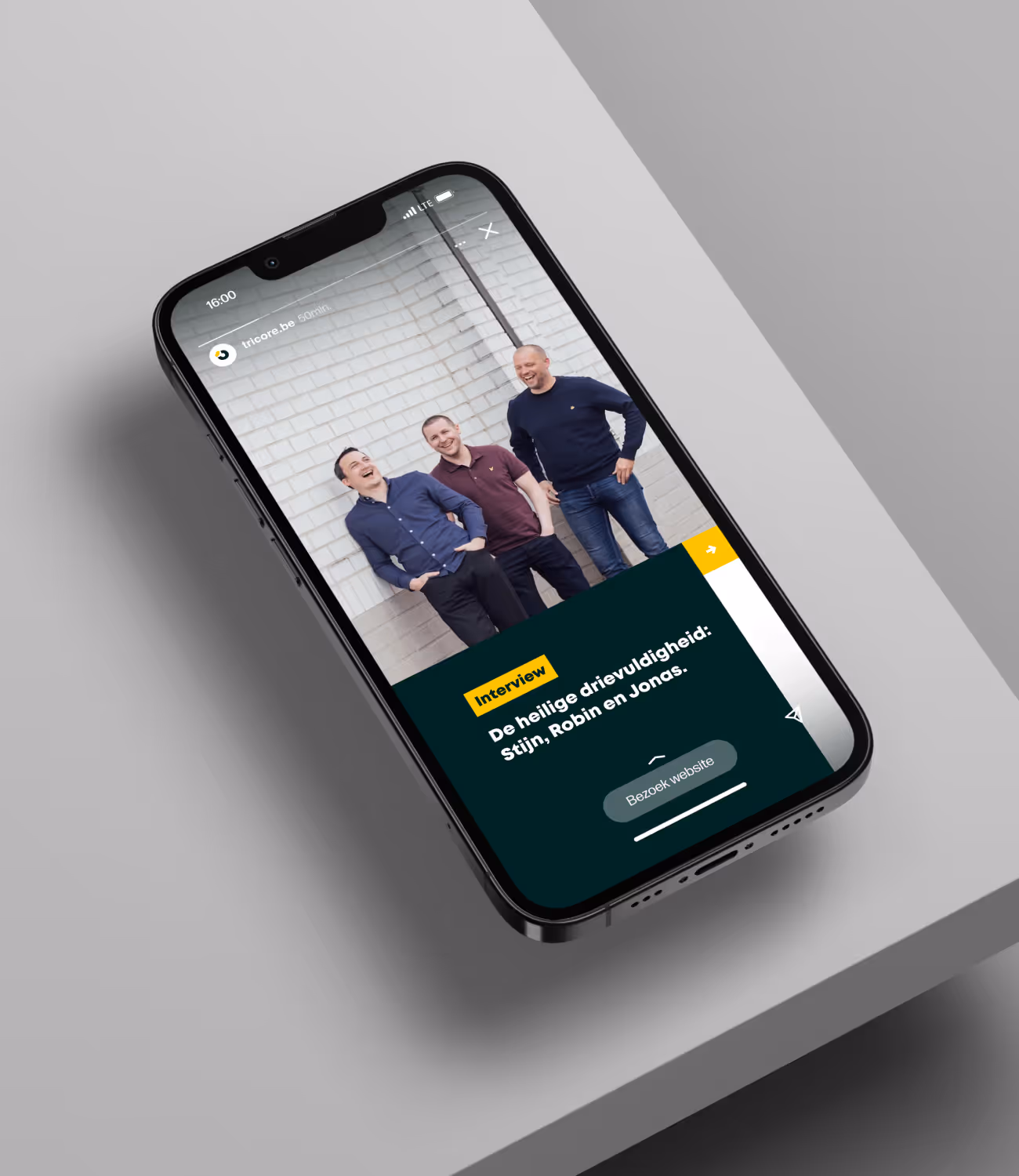 Smartphone toont interviewpagina van Tricore met drie medewerkers lachend voor witte muur.