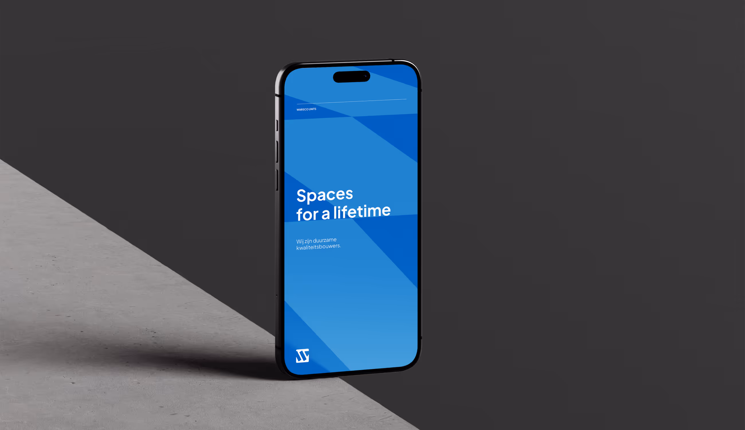 Smartphone toont Warsco-scherm met slogan “Spaces for a lifetime” op blauwe achtergrond, symbool voor duurzaamheid.