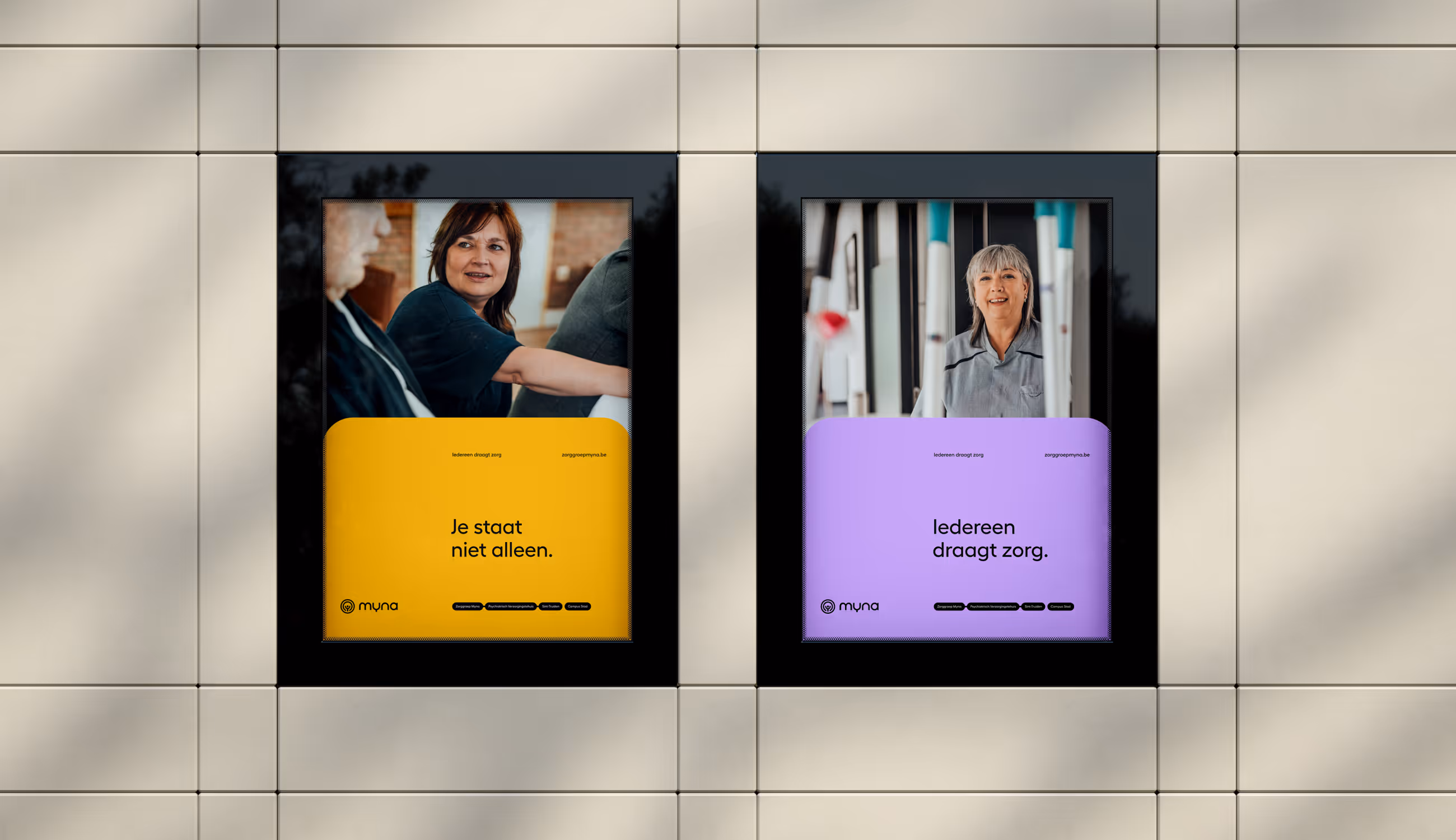 Twee Myna-posters naast elkaar aan gevelwand: links gele affiche met vrouw en tekst “Je staat niet alleen”, rechts paarse affiche met vrouw en tekst “Iedereen draagt zorg.”