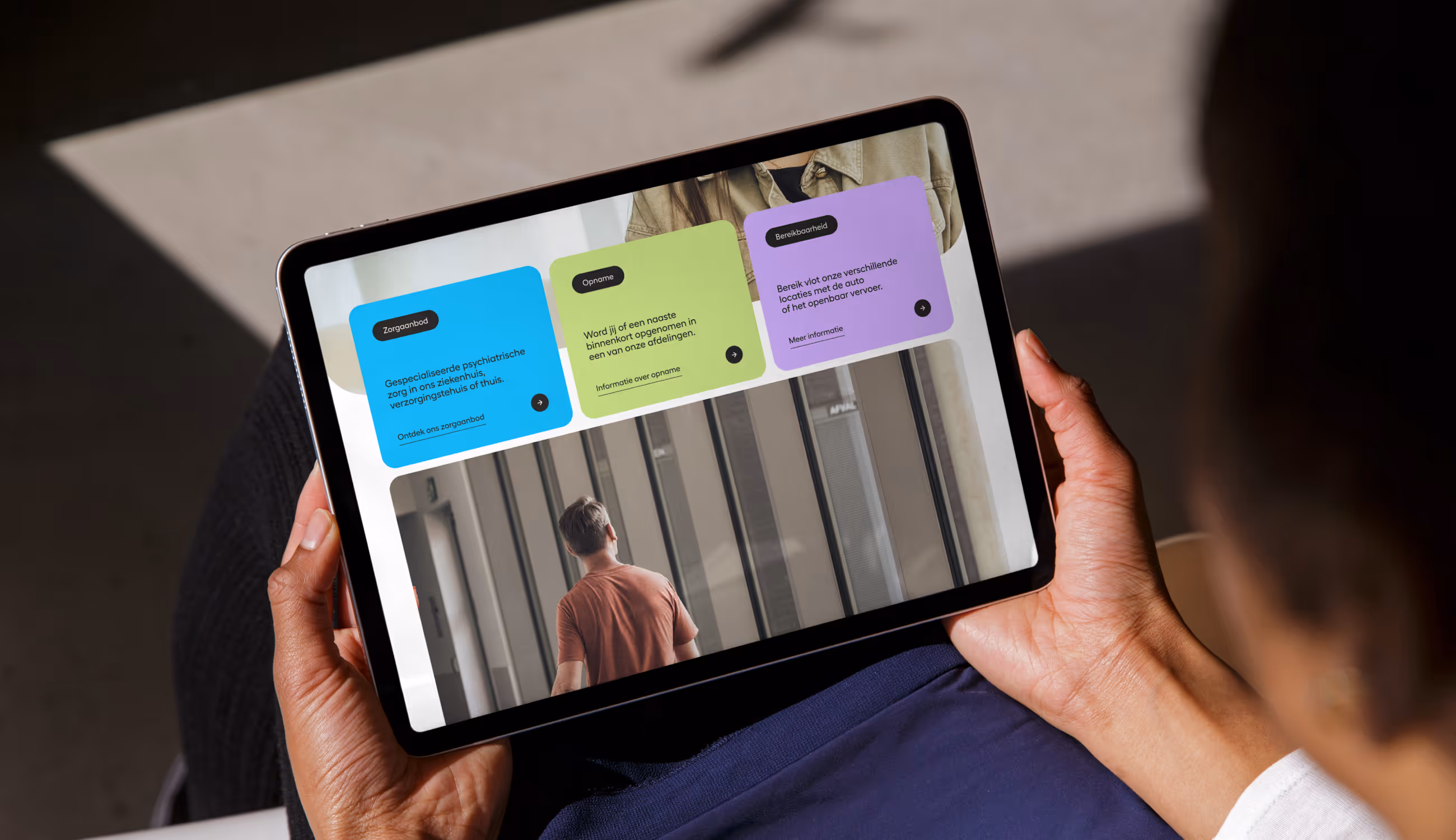 Persoon bekijkt Myna-website op tablet met kleurrijke blokken, toont moderne en gebruiksvriendelijke digitale interface.