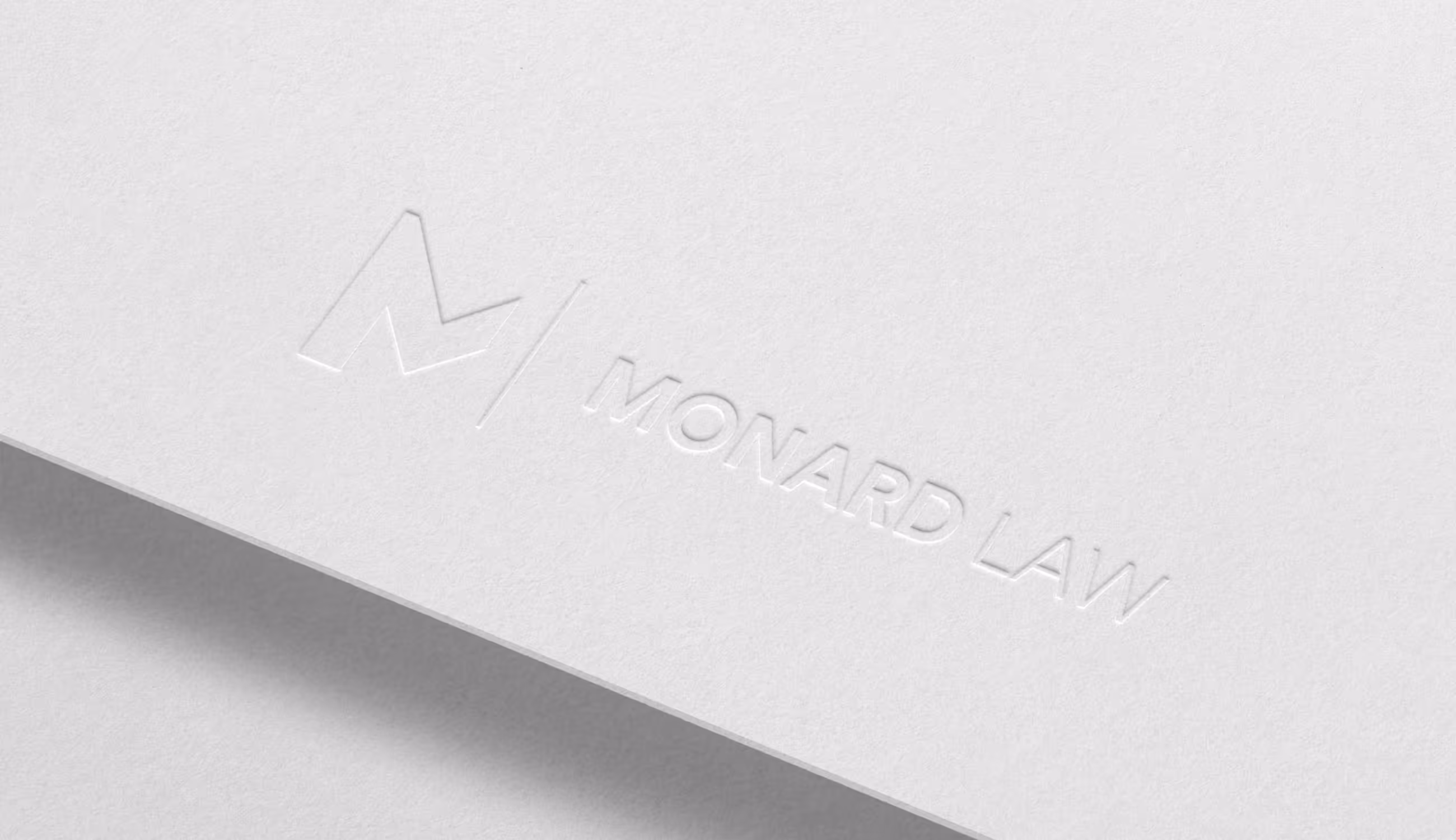 Wit reliëfdruk-detail van het Monard Law-logo op papier.