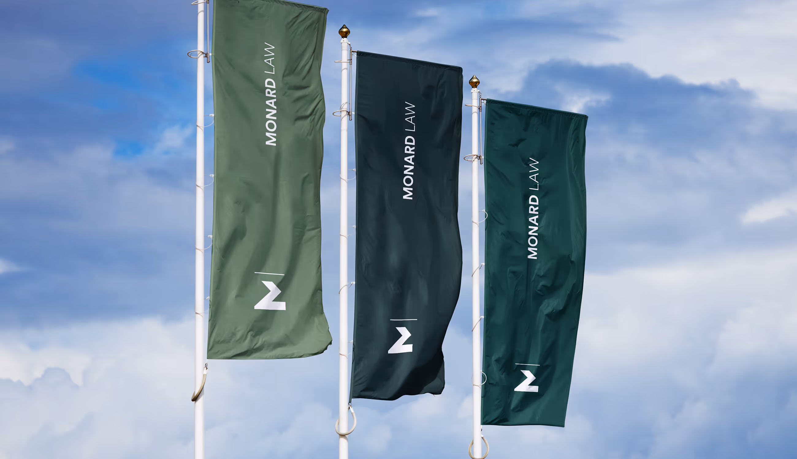 Drie Monard Law-vlaggen wapperend buiten in verschillende groentinten.