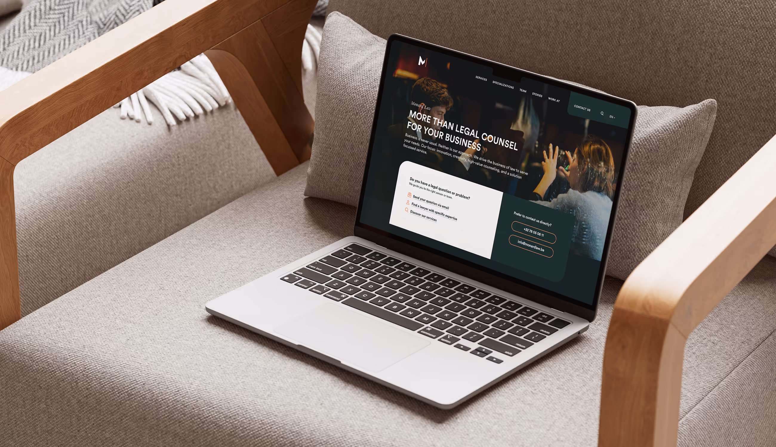 Laptop toont Monard Law-website op een beige zetel.