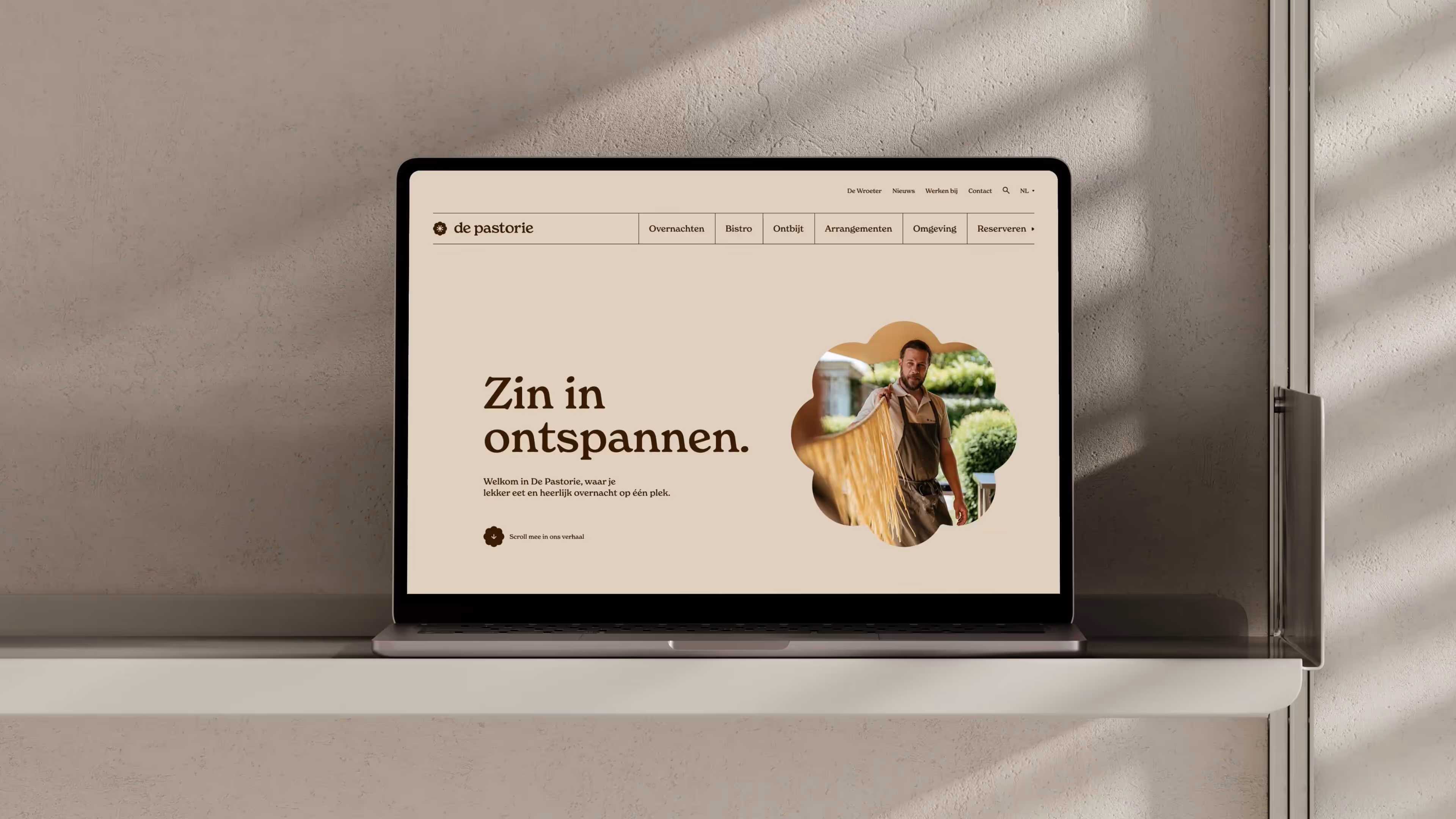 Laptop met de website van De Pastorie, submerk van De Wroeter, met warme beige tinten en een rustgevende hero-boodschap over ontspannen en overnachten.