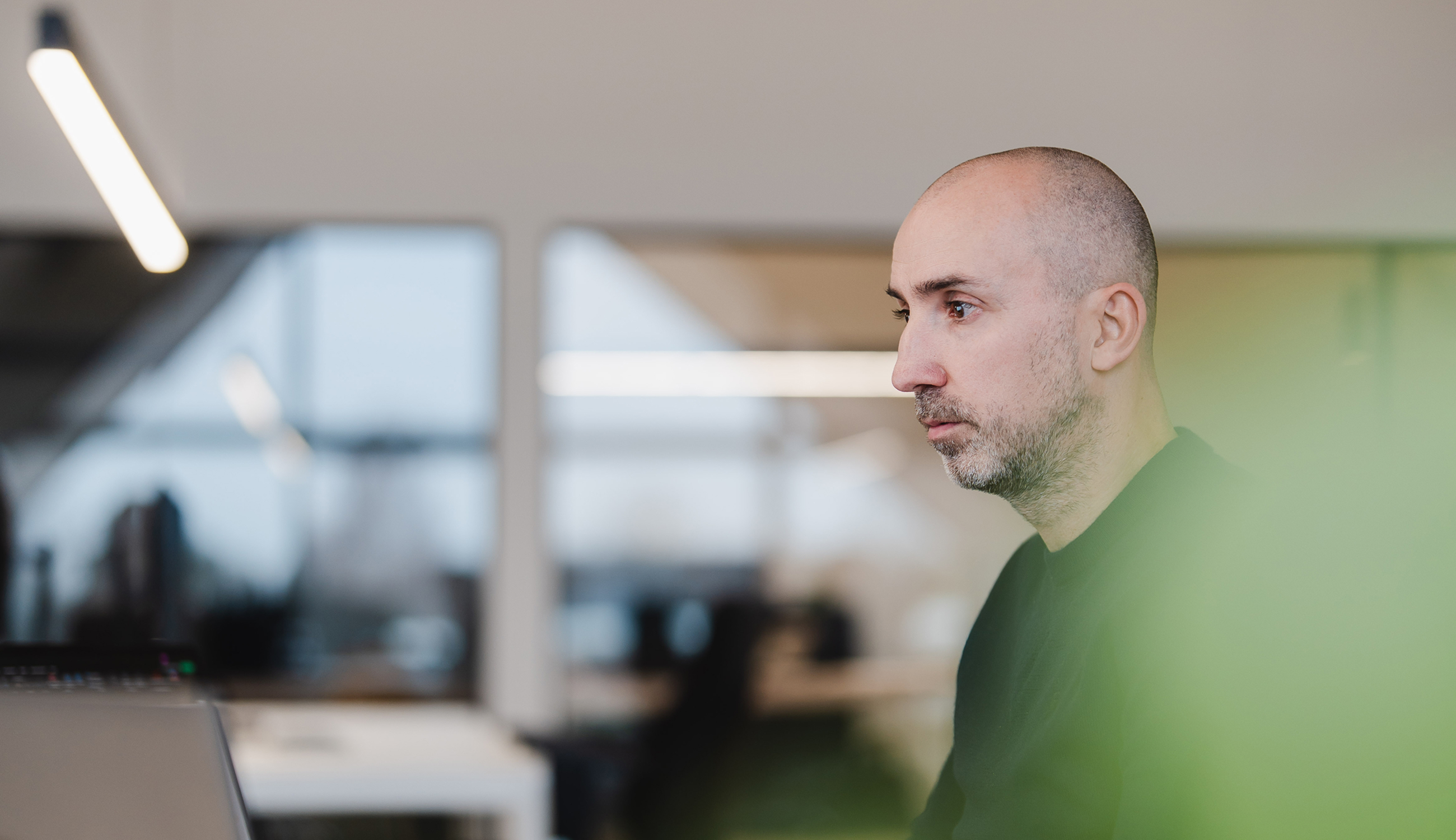 Portret van een mannelijke consultant aan het werk in een modern kantoor met subtiele groene voorgrondblur.