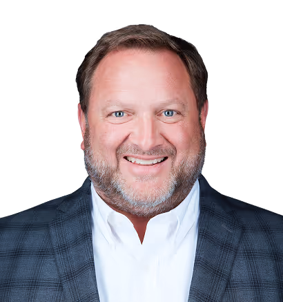 Smiling middle-aged man with short brown hair and beard, wearing a white shirt and dark checkered blazer.