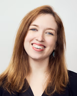 Smiling woman with long light brown hair wearing a black top.