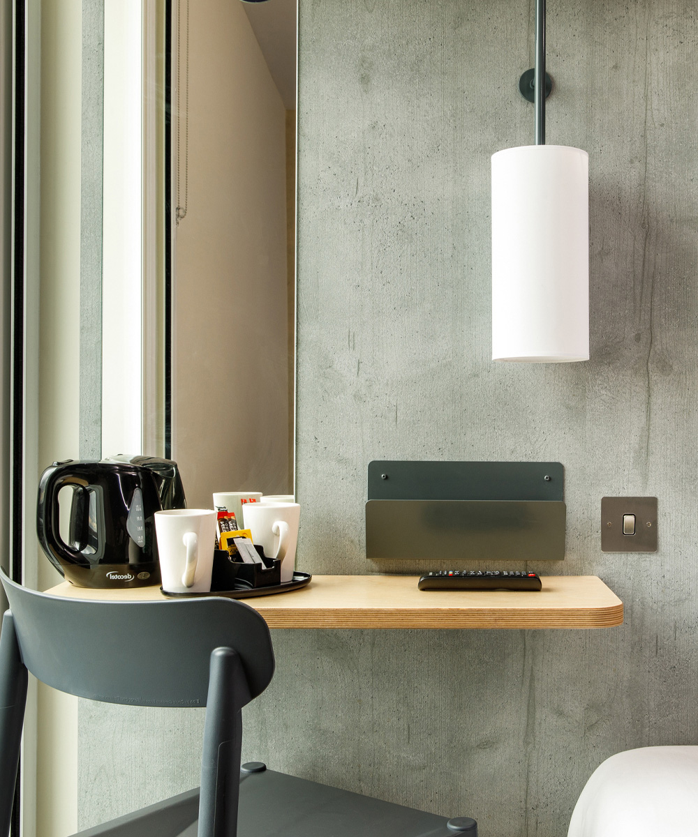 Compact Ibis Hotel room desk area with coffee-making facilities and contemporary lighting