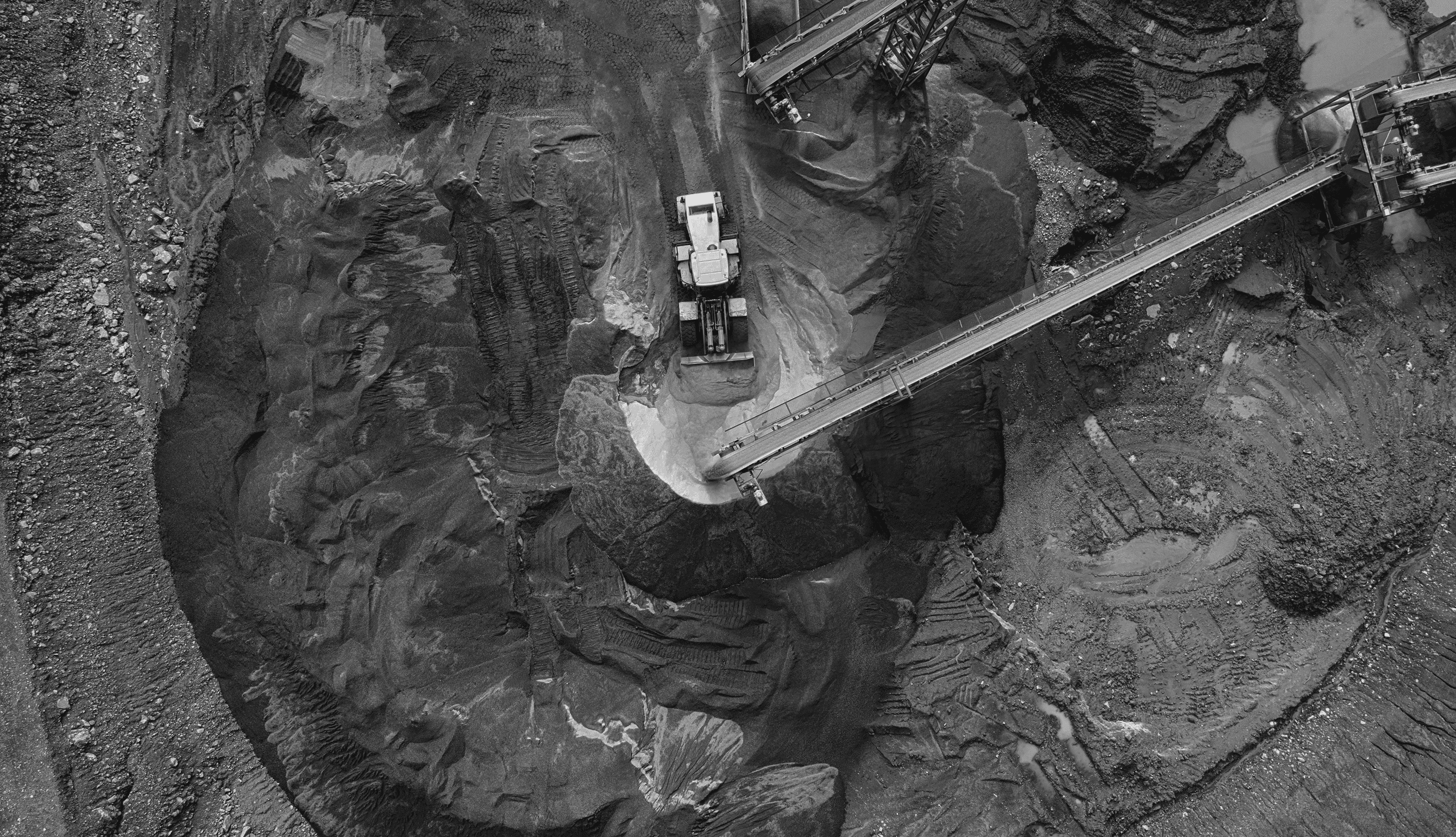 Aerial view of a mining site with heavy machinery and conveyor belts moving extracted material.