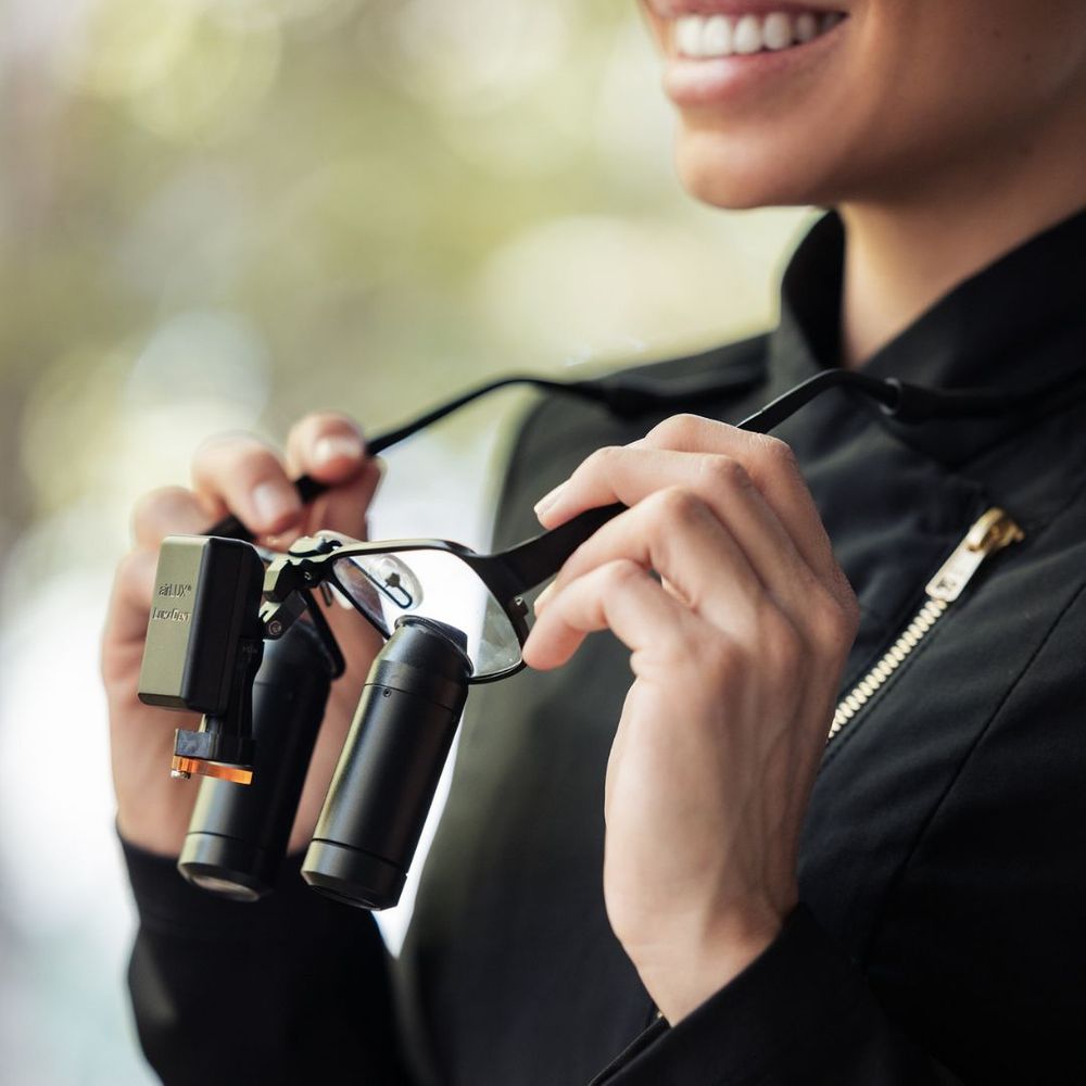 Dentist wearing special magnifying glasses, smiling. 