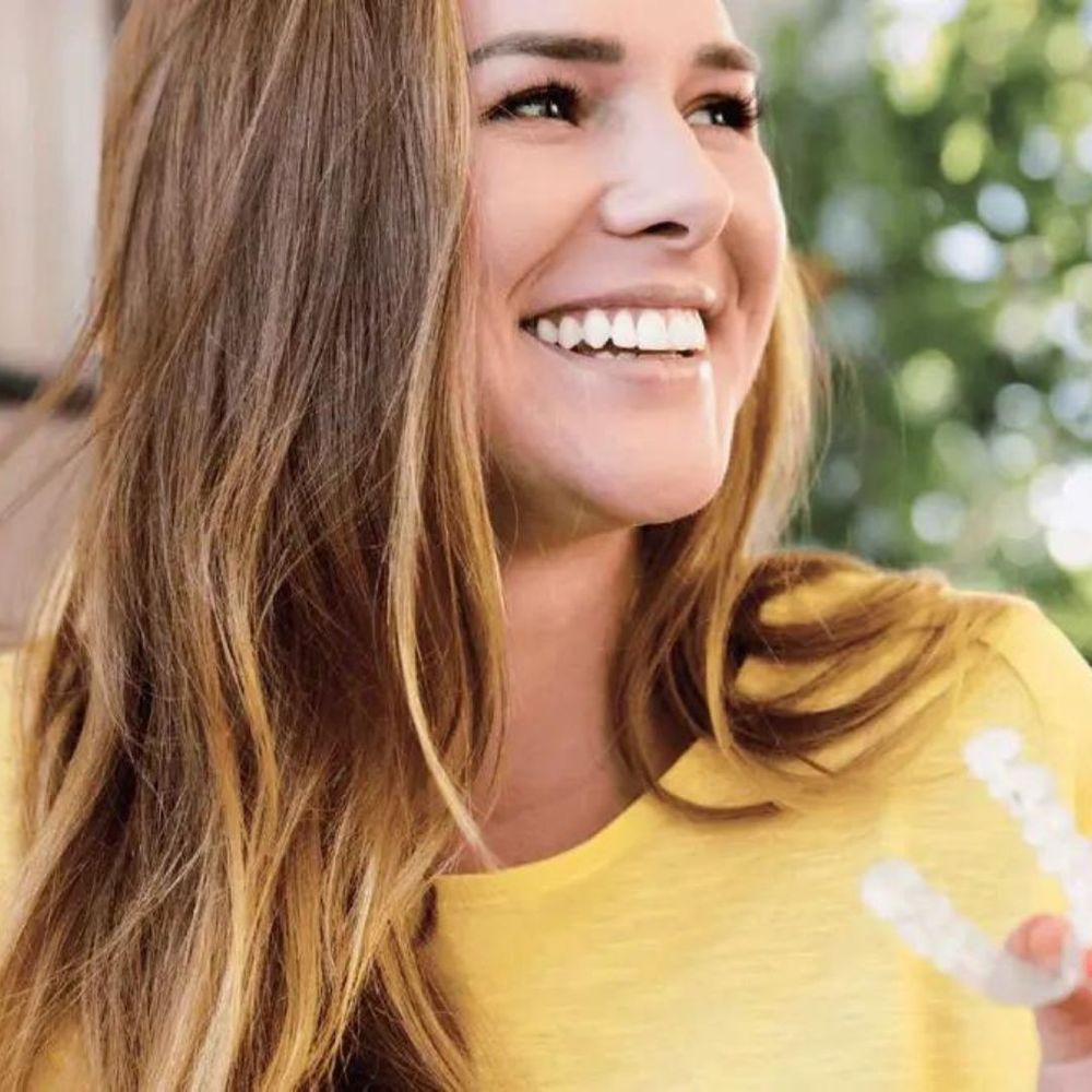 Woman holding Invisalign trays and smiling