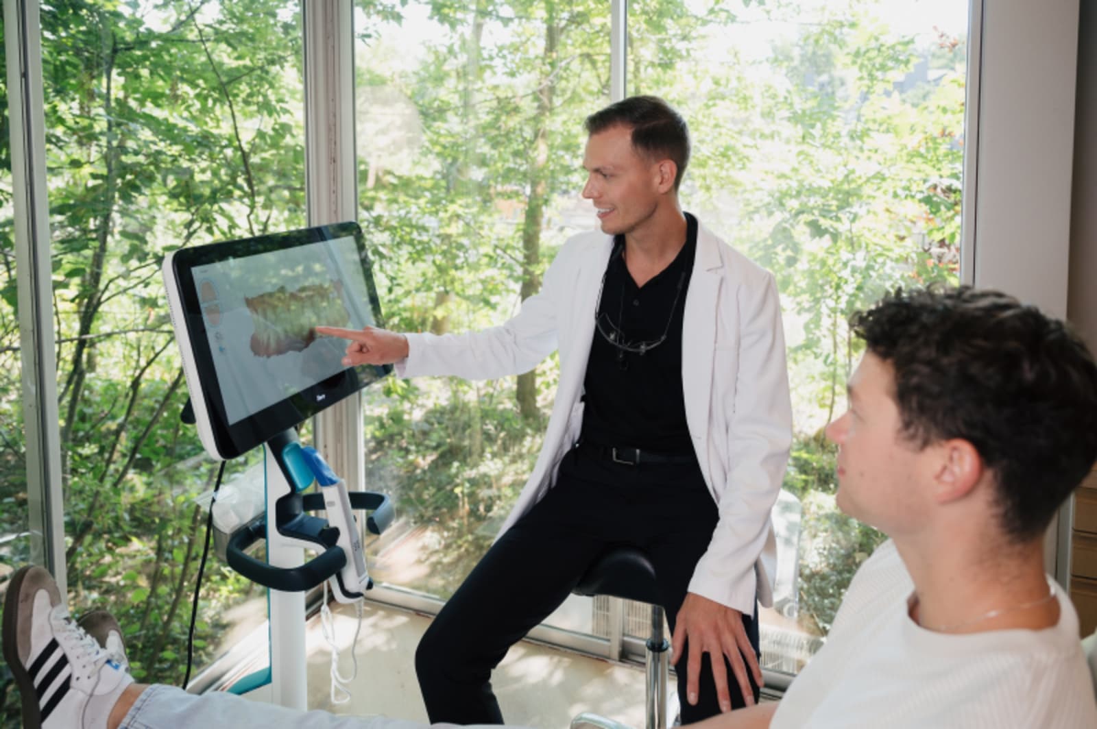 Dentist showing digital implant design on tablet screen to patient during consultation