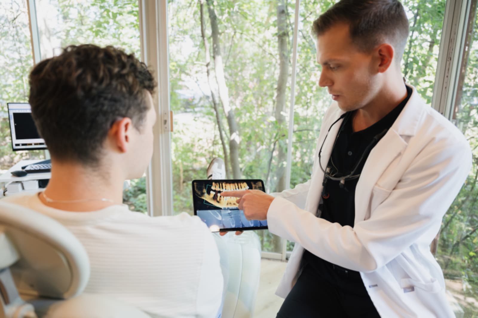Dentist explaining dental procedure to patient using digital display