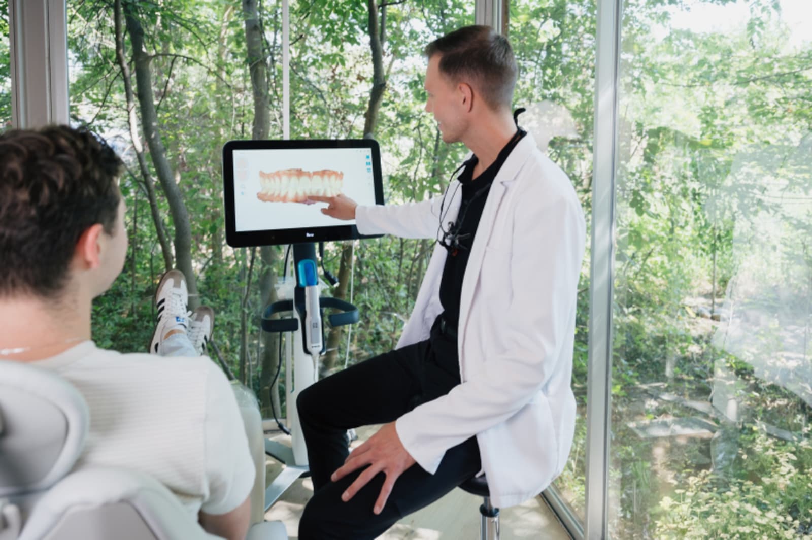 Dentist showing digital treatment plan on computer screen to seated patient