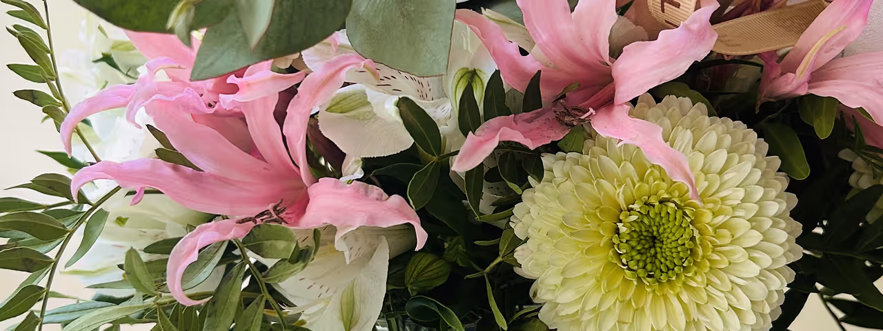 Bouquet of flowers including pale pink roses, light green chrysanthemum, pink lilies, and eucalyptus leaves.