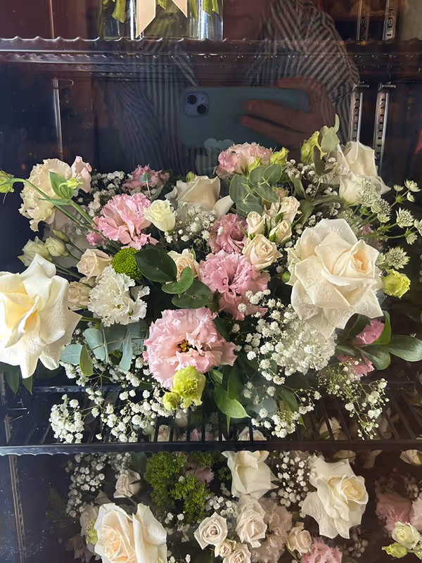 Bouquet of white, pink, and green flowers including roses and baby's breath inside a glass display case.