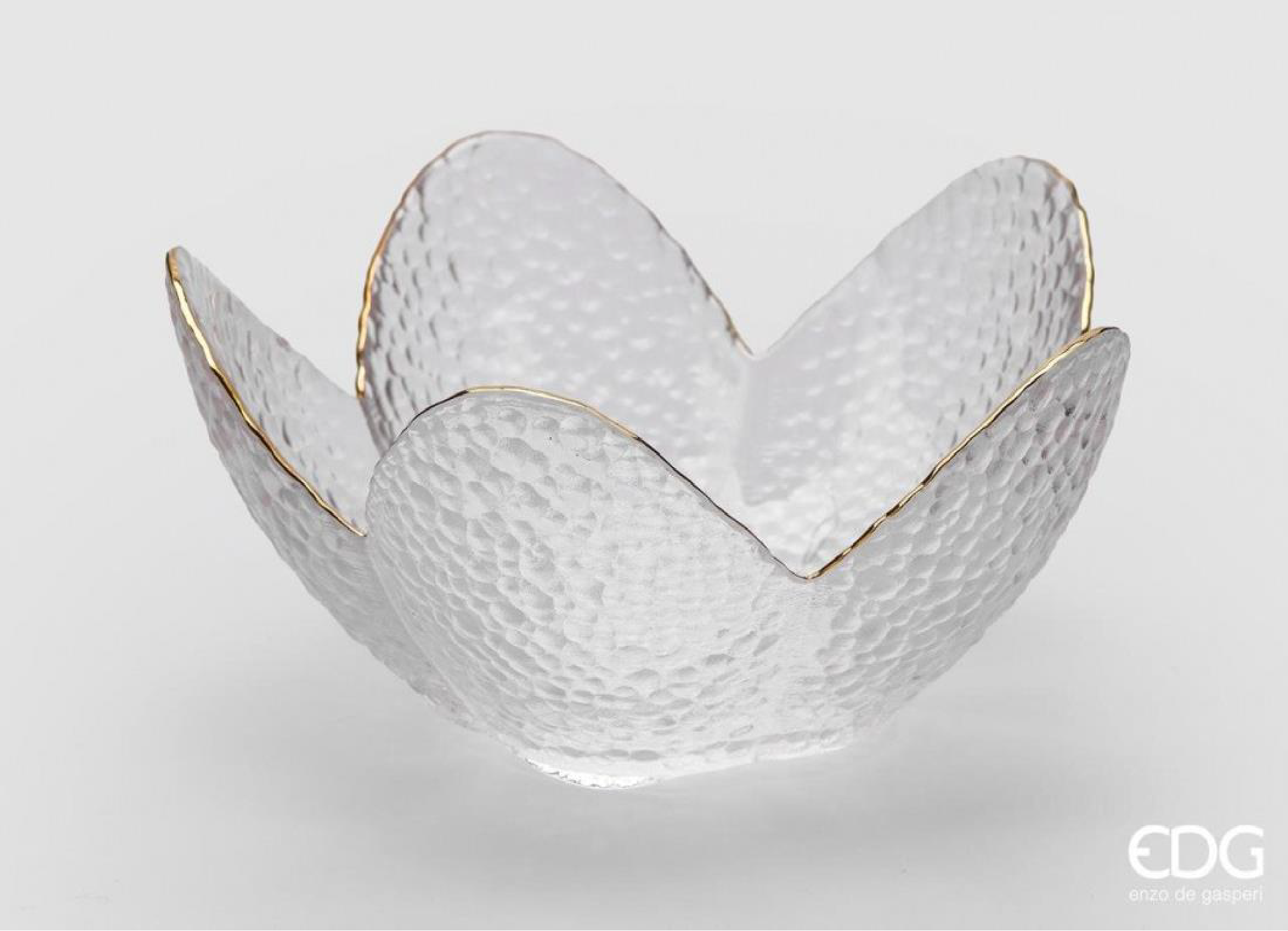 A decorative candy bowl shaped with soft, petal-like edges that create a light and sculptural form. Made from natural textured glass with a subtle gold trim, it reflects light gently and adds a refined detail to any table or shelf. Suitable for serving sweets, fruits, or small treats, or as a decorative piece in everyday settings. 