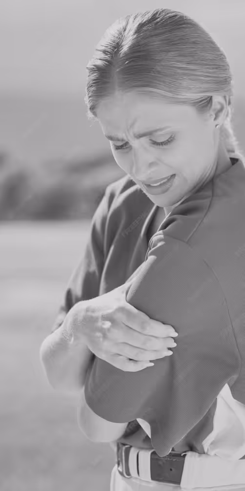 Woman outdoors grimacing and holding her right shoulder in pain.