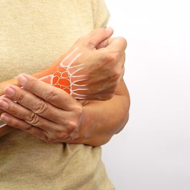 Person holding wrist with overlay showing wrist bones and joint pain area in red.