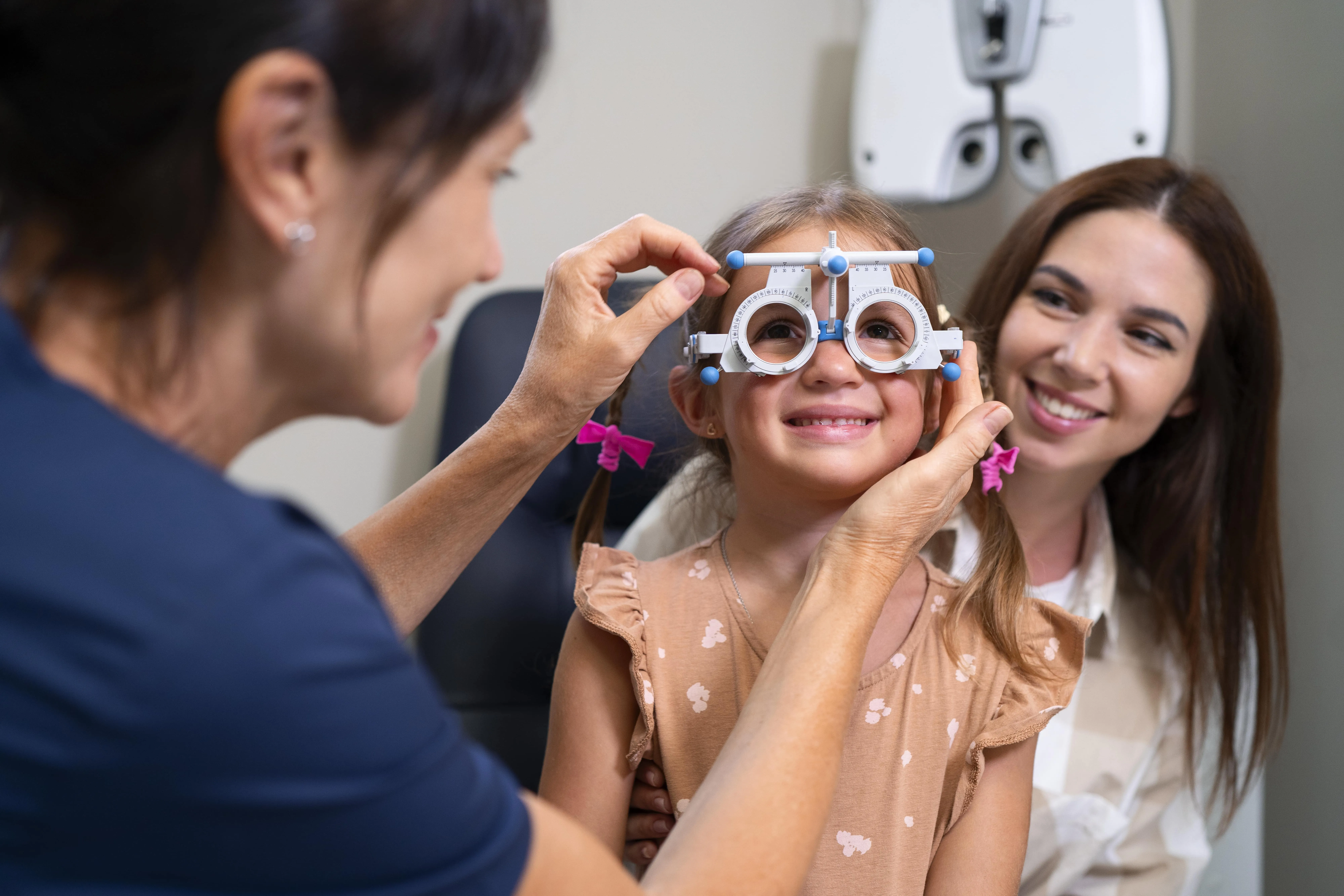 Optometrist fitting child with phoropter during eye examination at clinic