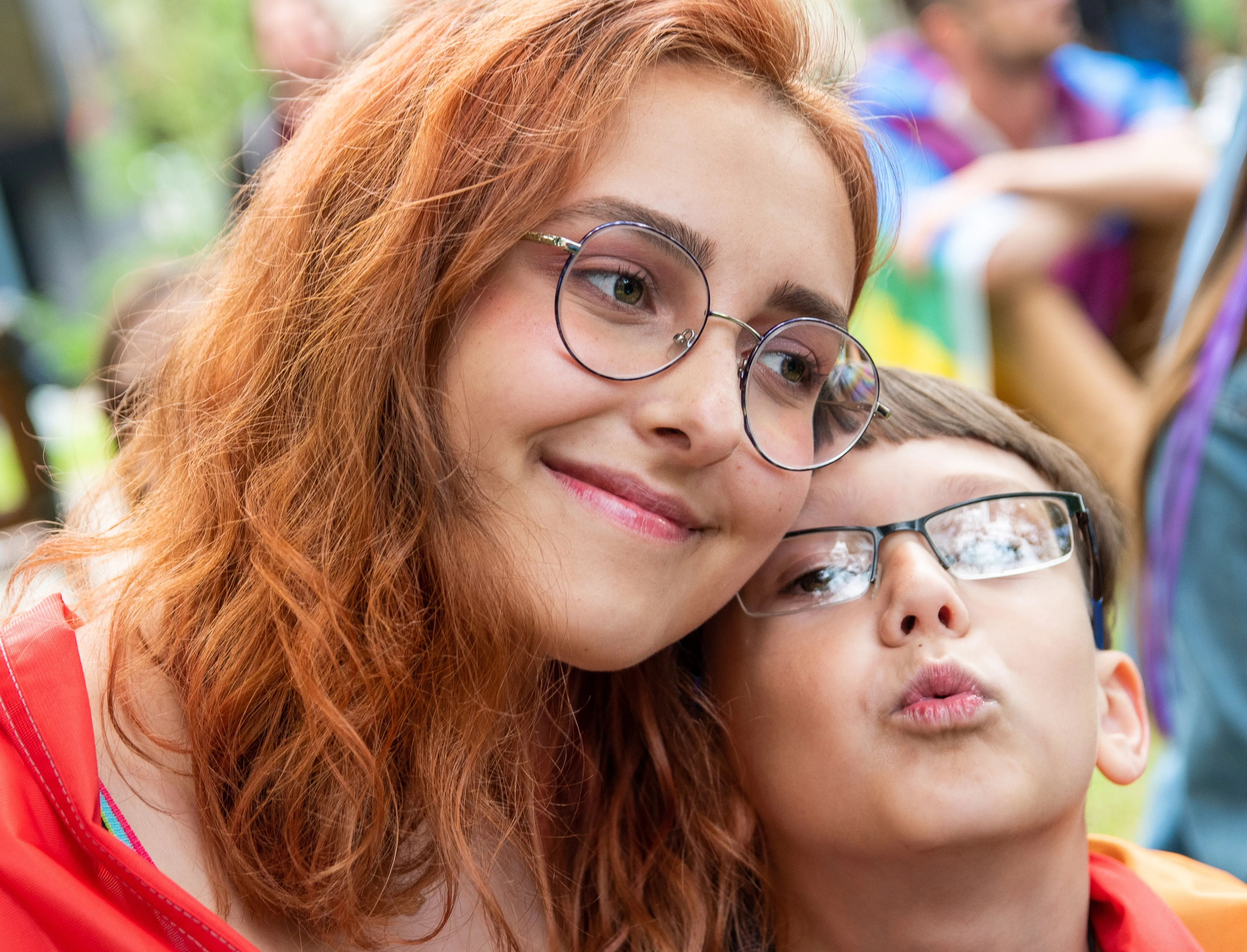 Woman with red hair and boy wearing glasses smiling together outdoors