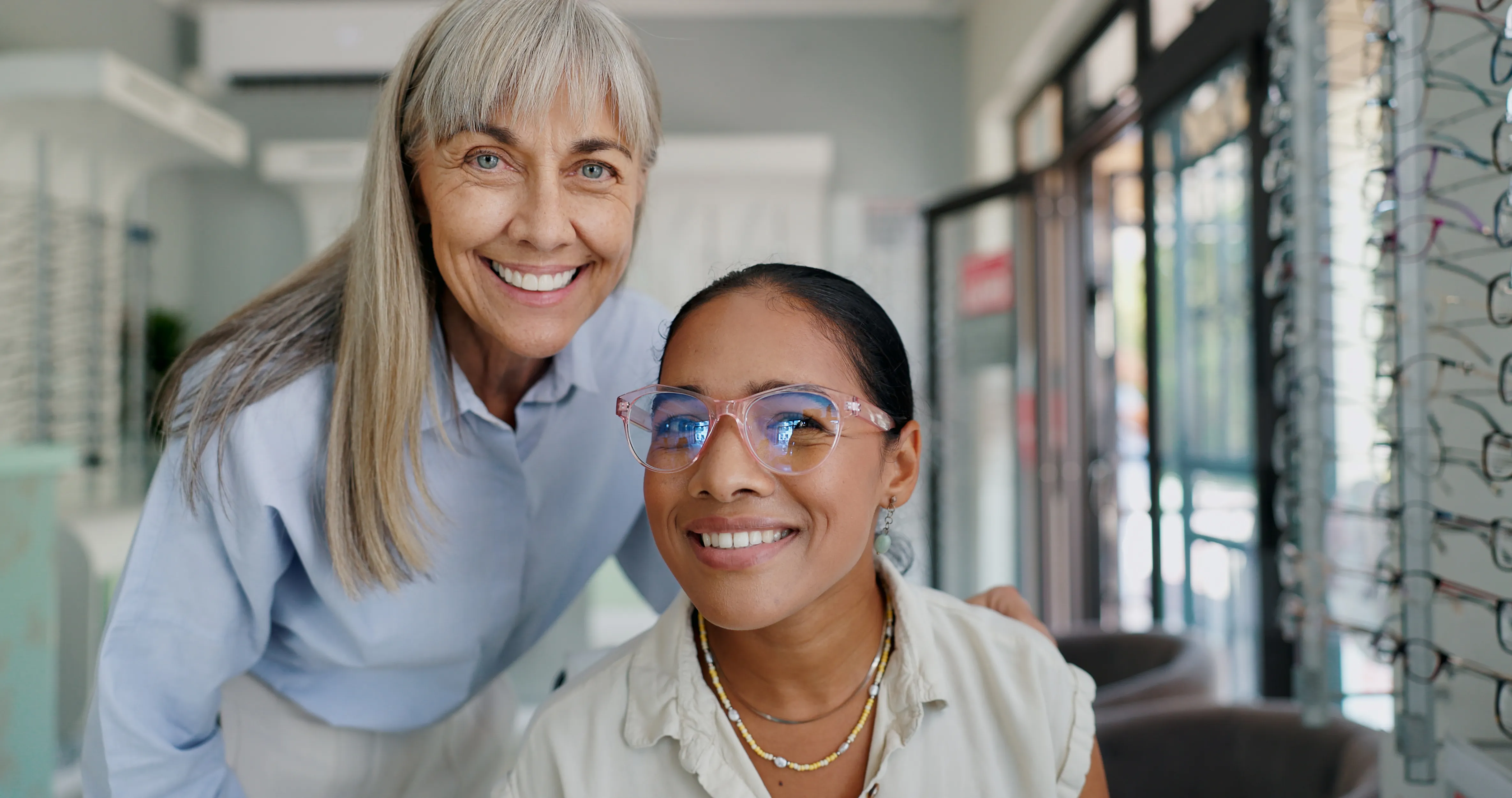 Two women smiling in a modern office with data displays on walls.