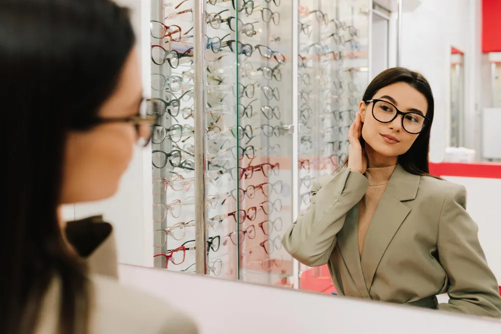Woman trying on eyeglasses at optometrist store with display of frames