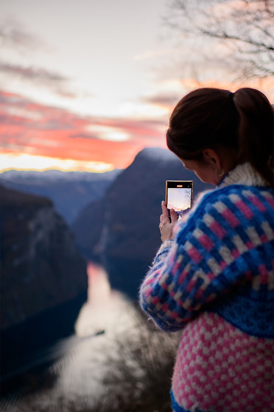 Dame tar bilde av fjorden i solnedgang