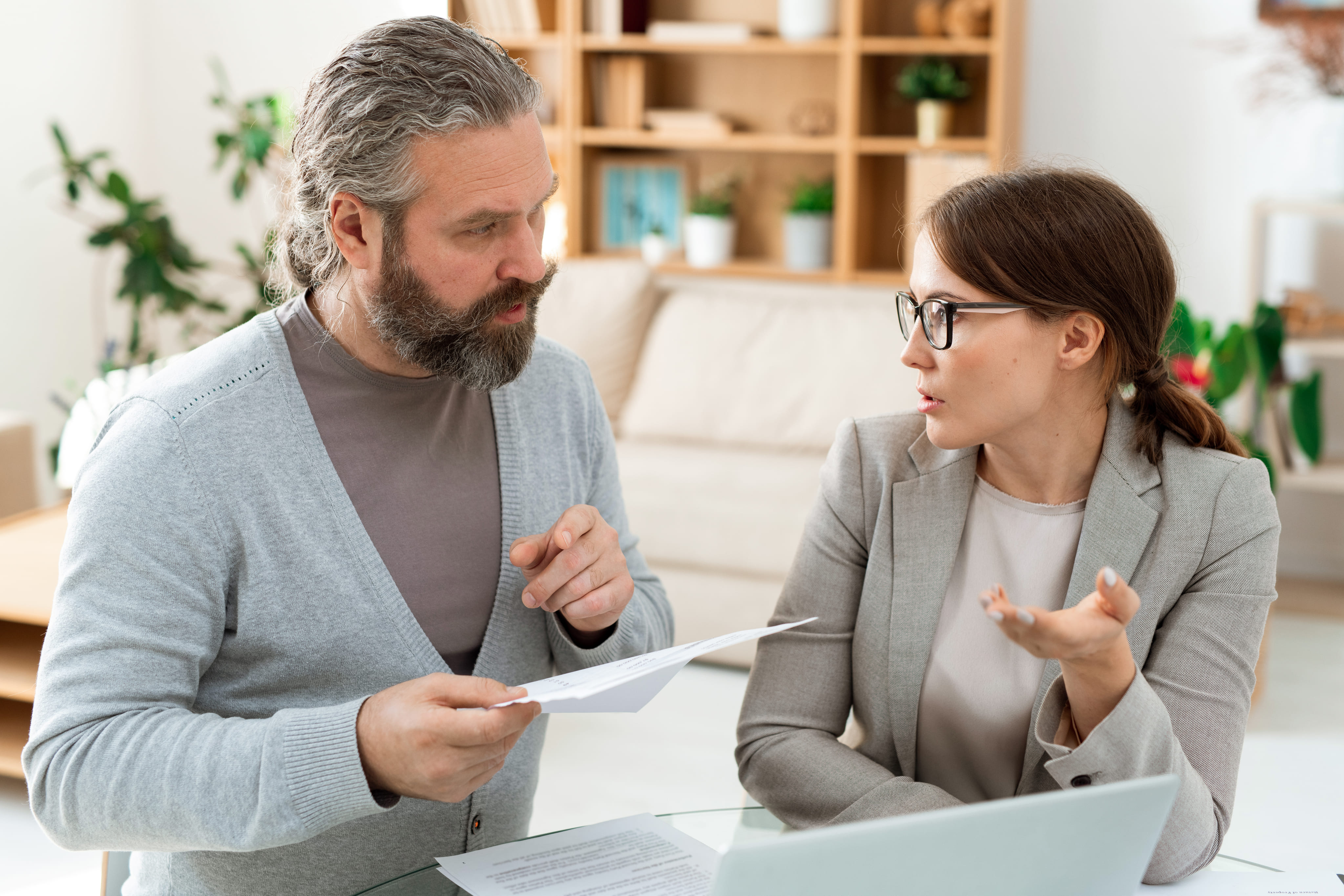 A real estate attorney holding documents while speaking with a couple outside of a modern residential home