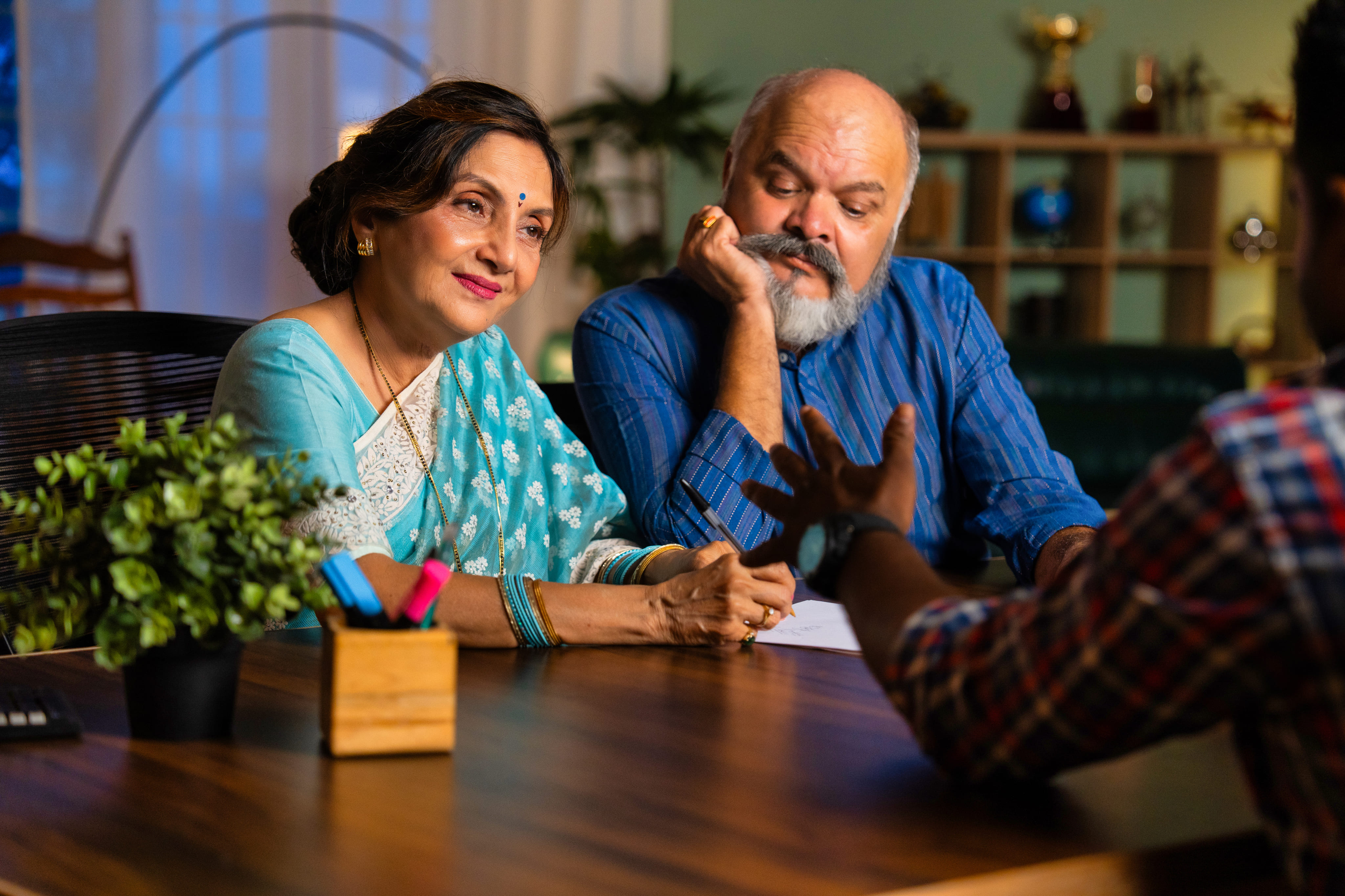 A male attorney in a suit reviewing information on a tablet with an elderly couple in an office.
