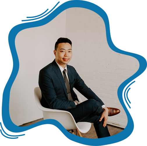 Professional portrait of a male corporate attorney in a dark suit sitting in a modern white chair.