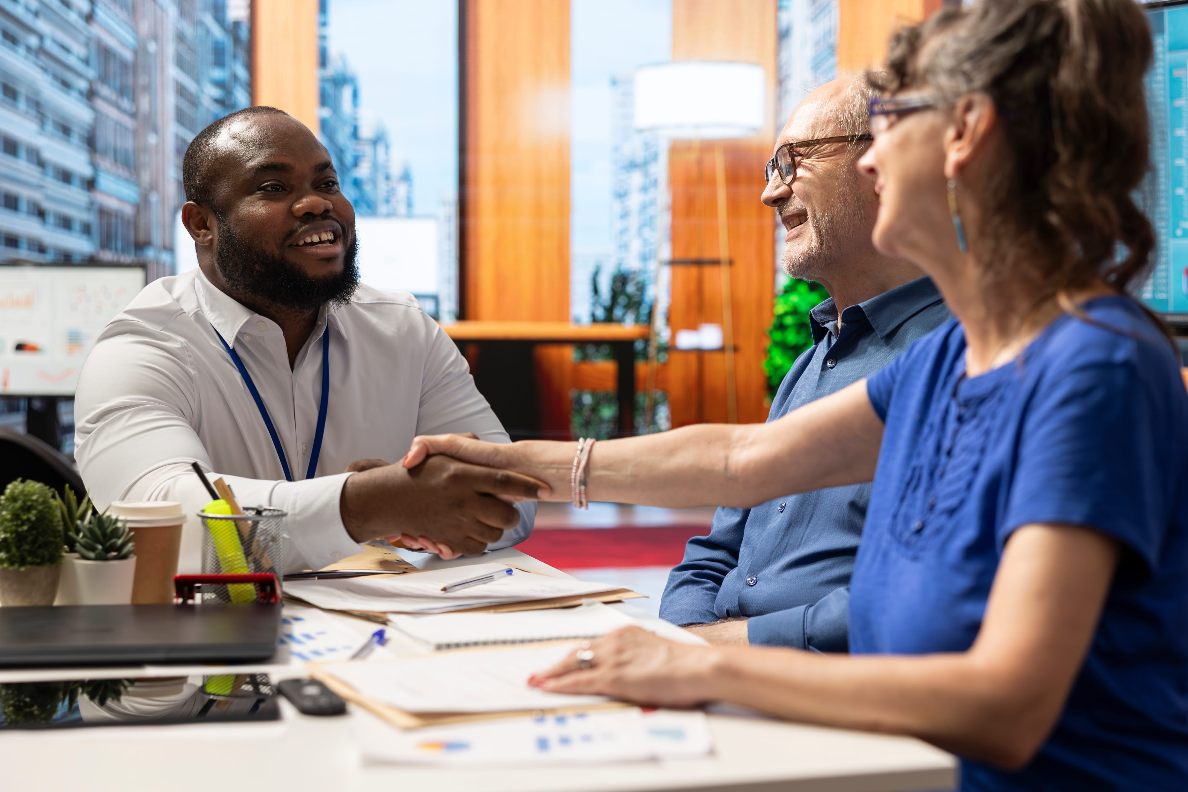A smiling professional shaking hands with a client during a successful meeting at a conference table.