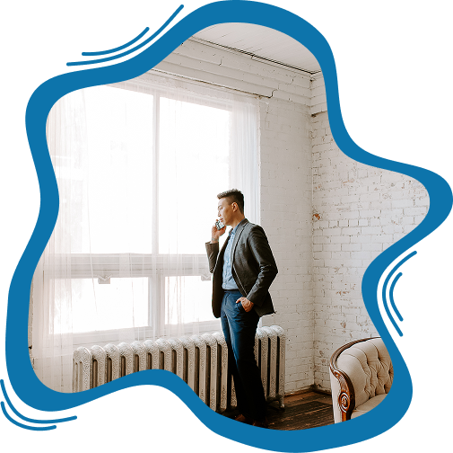 An attorney in a blazer talking on a mobile phone while standing by a large, bright window in a loft-style office.