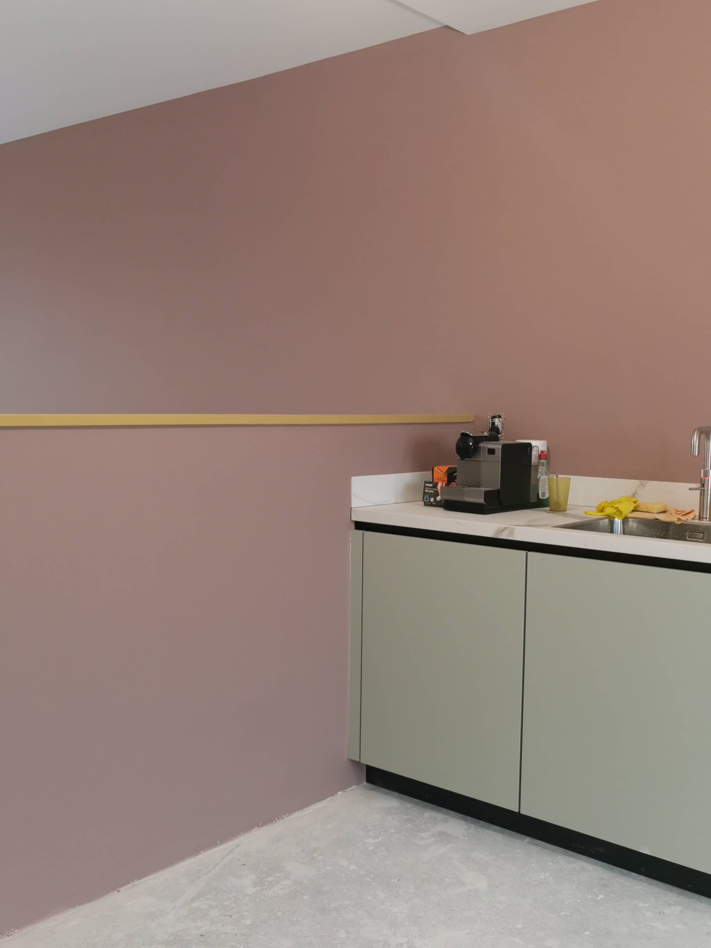 Kleine pantry of keukenhoek met een roze-achtige muur en een lichtgroen onderkastje, modern schilderwerk interieur.