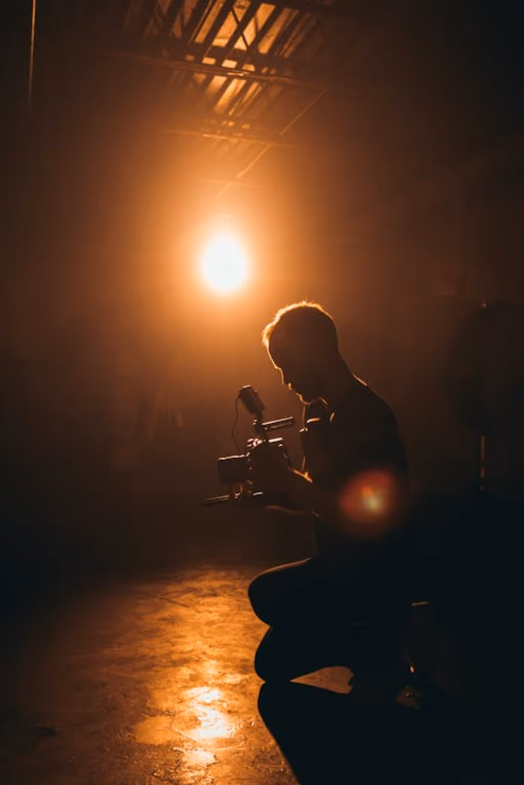 Man holds a camera with a bright lightbulb illuminating a dark room 
