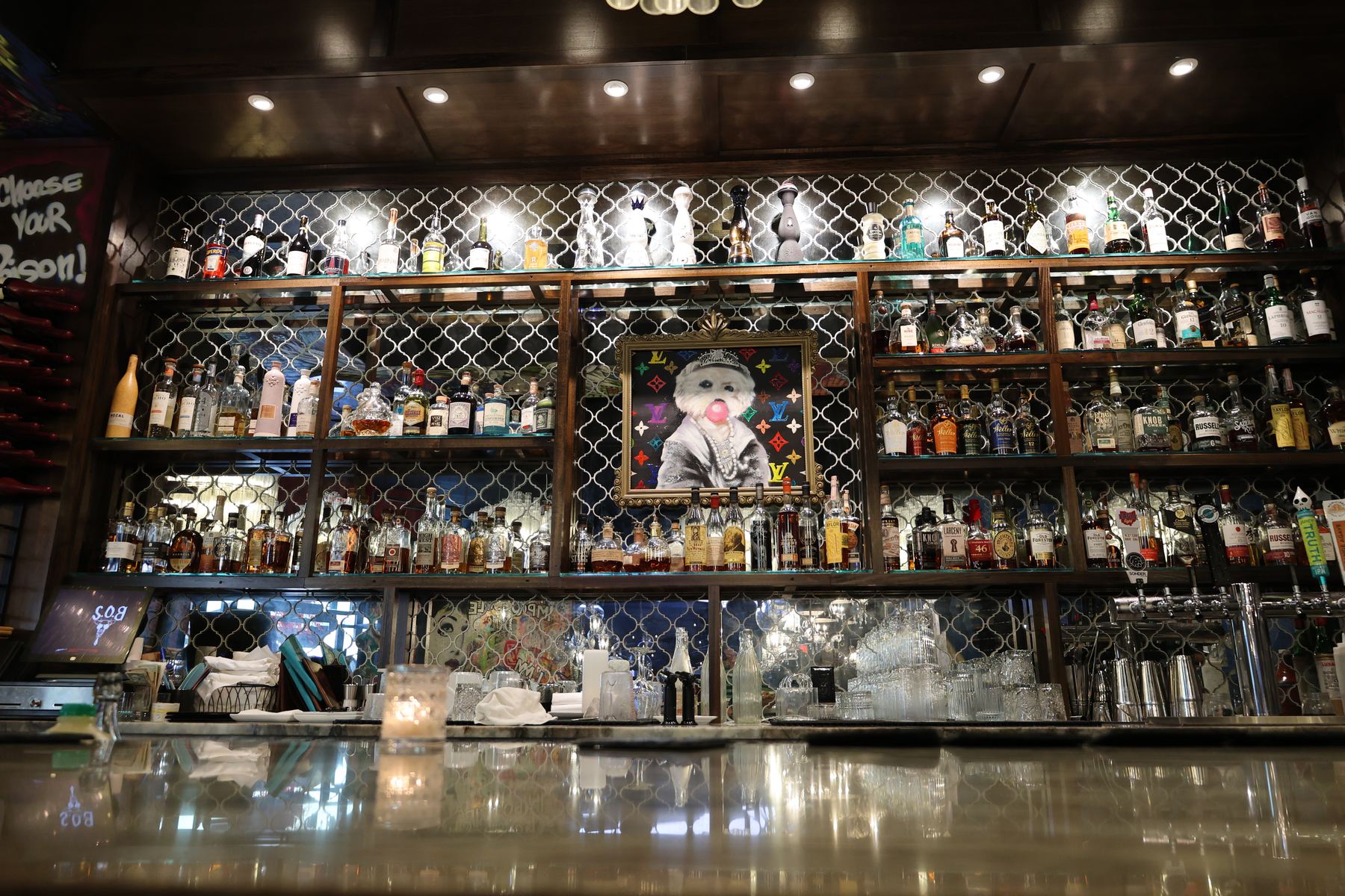 The back bar at S.O.B. Steakhouse, glass shelving lit against a diamond-mirrored wall