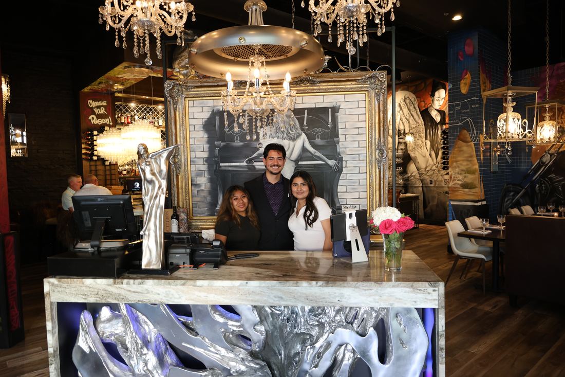 The S.O.B. team welcoming guests at the host stand beneath a crystal chandelier