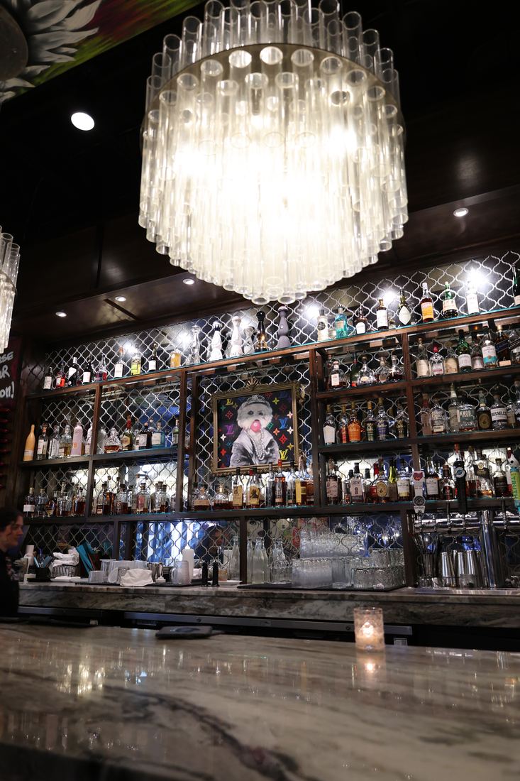 The back bar at S.O.B., rows of spirits lit behind mirrored diamond paneling