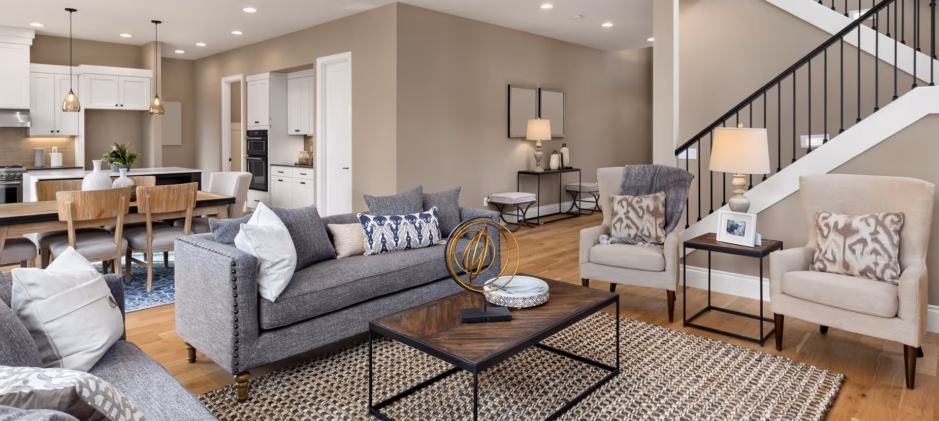 Modern Richmond living room with warm honey-toned hardwood floors, gray furniture, and open concept layout to kitchen
