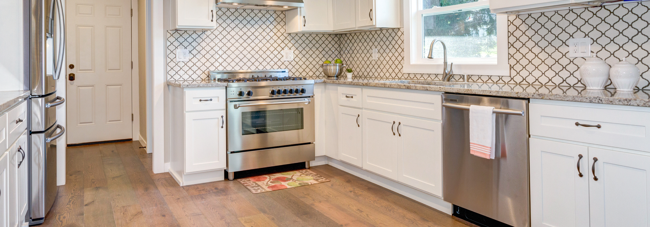 Luxury vinyl plank flooring in natural oak tones installed in a bright Richmond kitchen with white cabinets and stainless appliances