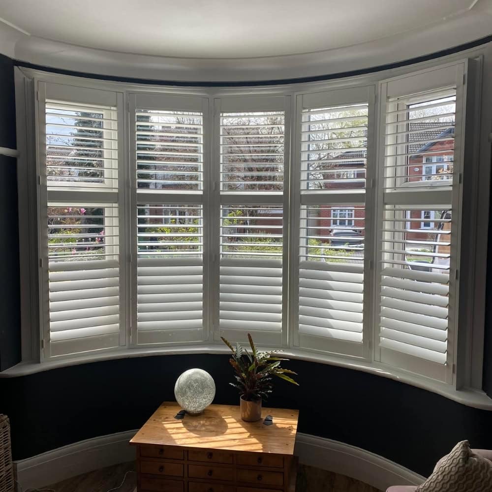 white finished bay window shutters in a blue living room