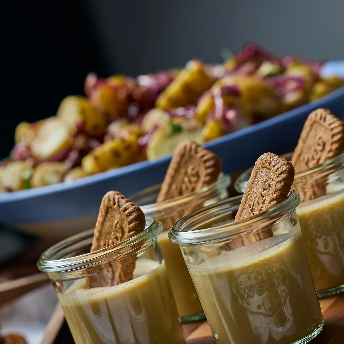 4 individual desserts with some snacks in the background.