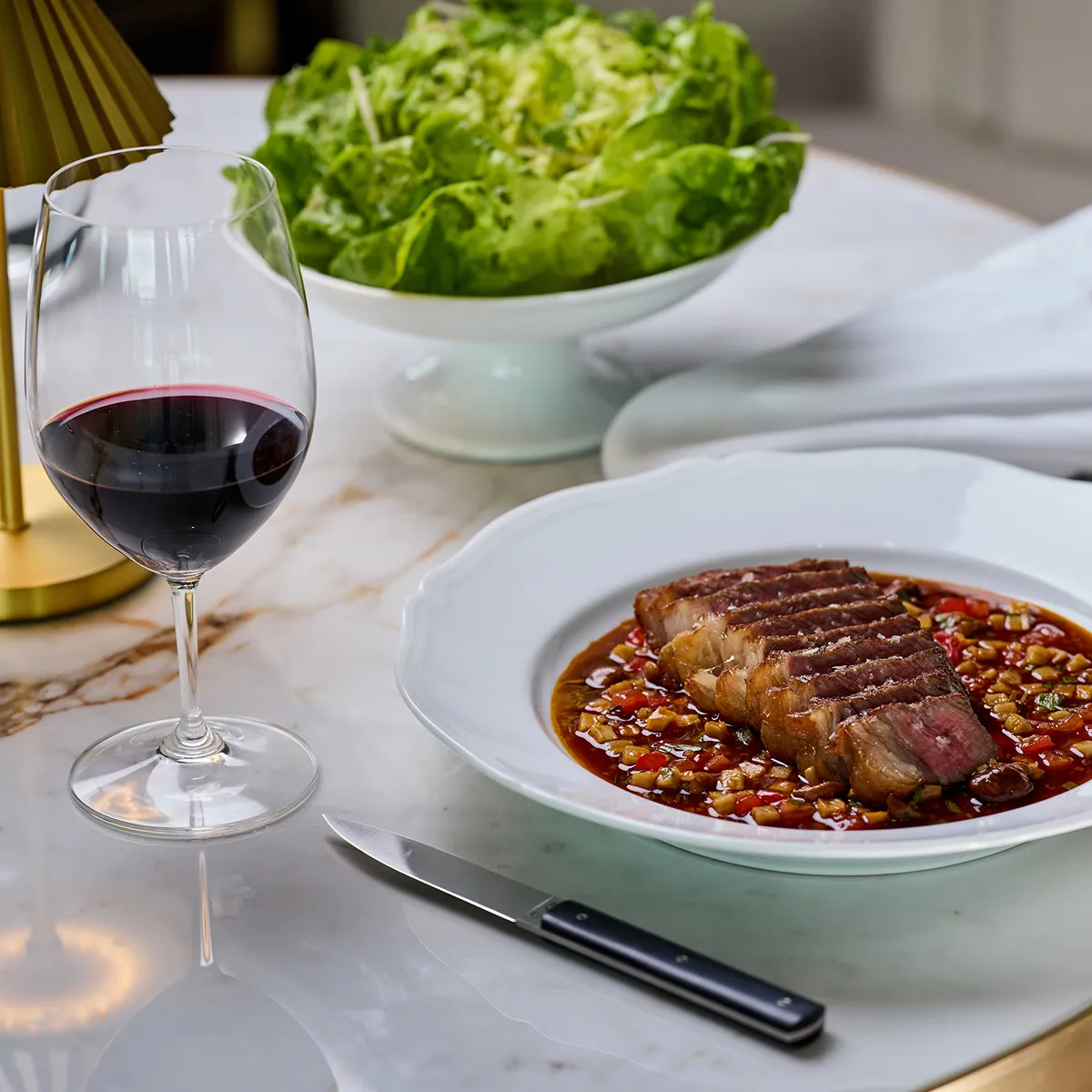 A bowl of food with a glass of red wine and some leaves.