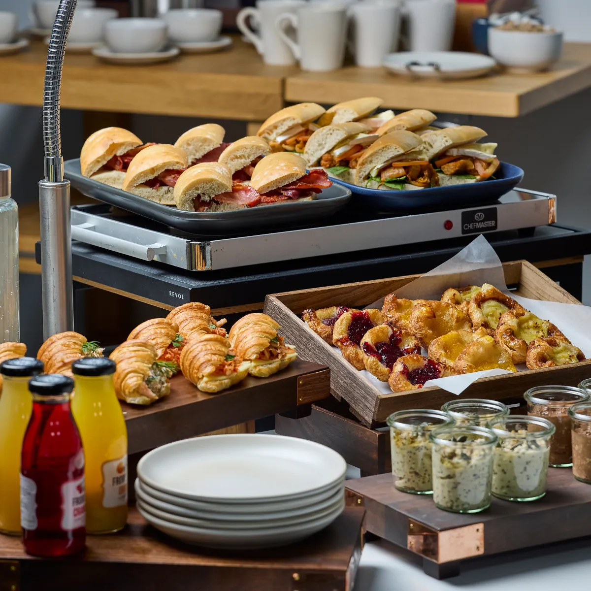 A buffet of rolls, snacks and drinks in a professional setting.